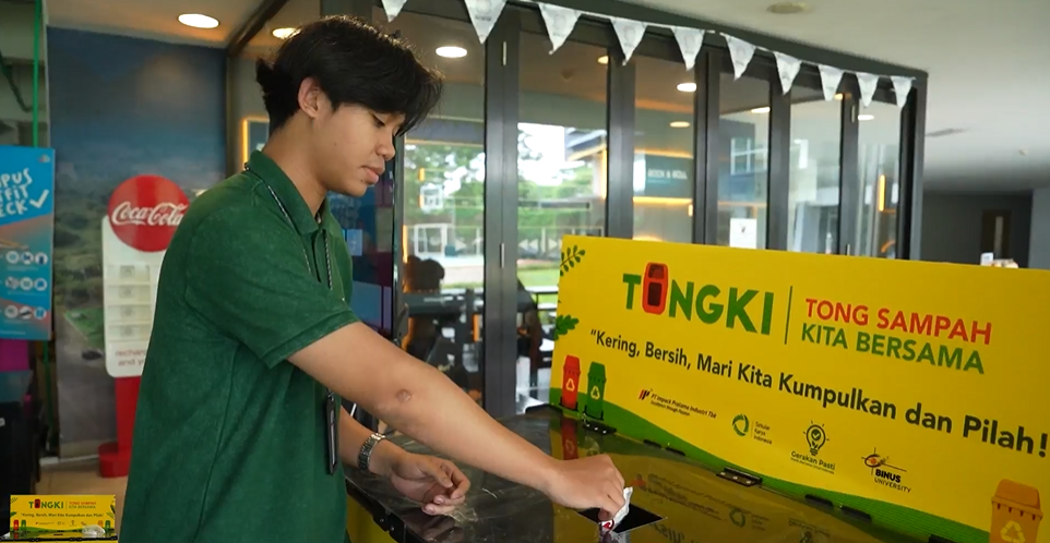 Seorang mahasiswa membuang sampah plastik yang terpilah, bersih, dan kering ke dalam TONGKI—mendukung kebiasaan berkelanjutan di lingkungan kampus.